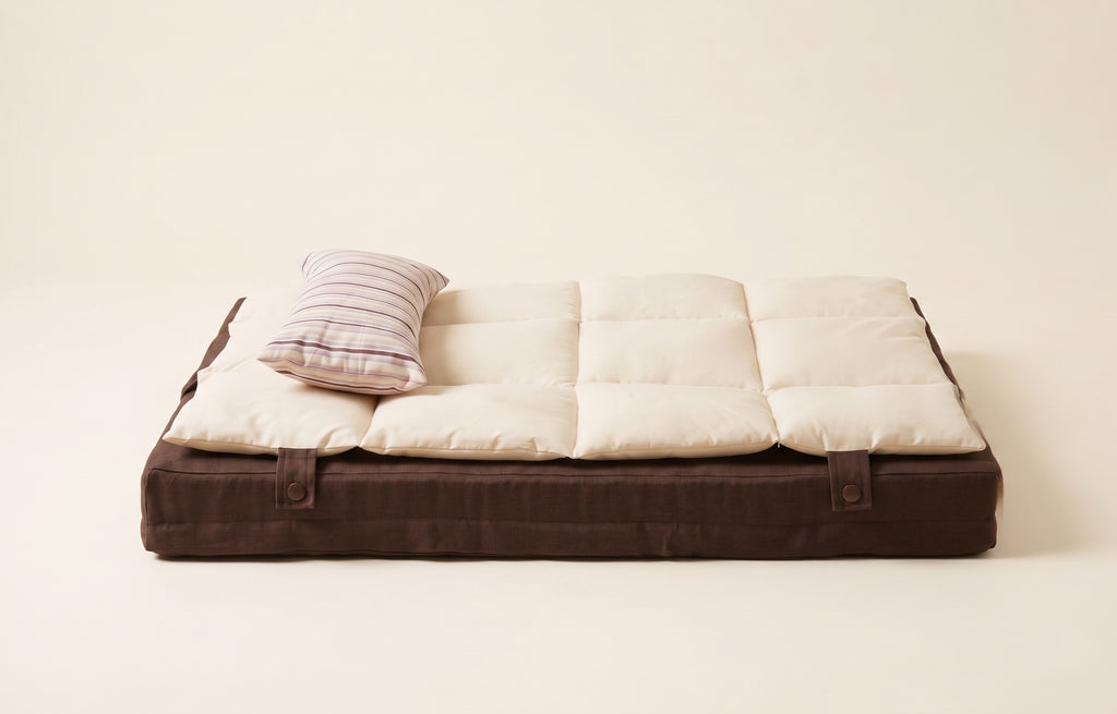 Foldable mattress with brown frame and white cushion on a light background
