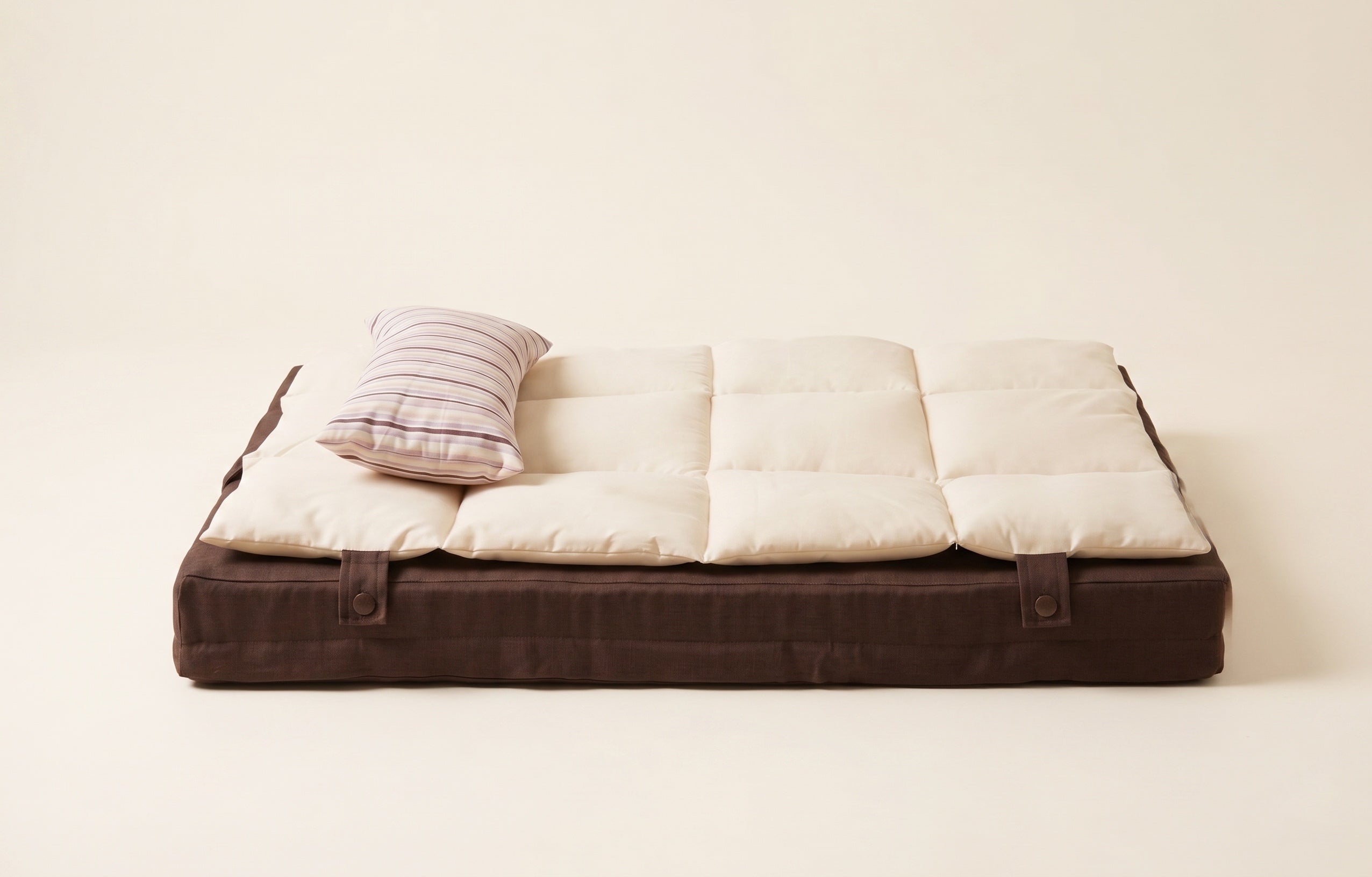 Foldable mattress with brown frame and white cushion on a light background