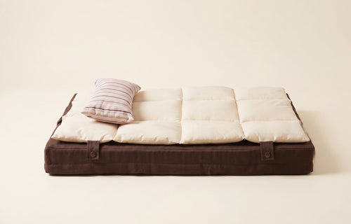 Foldable mattress with brown frame and white cushion on a light background
