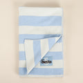 Folded blue and white striped blanket with a logo on a beige background