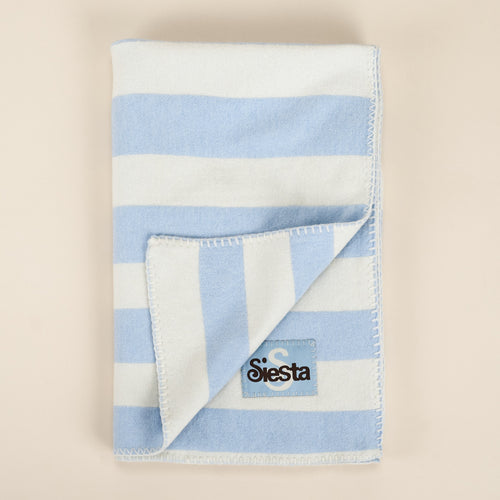 Folded blue and white striped blanket with a logo on a beige background