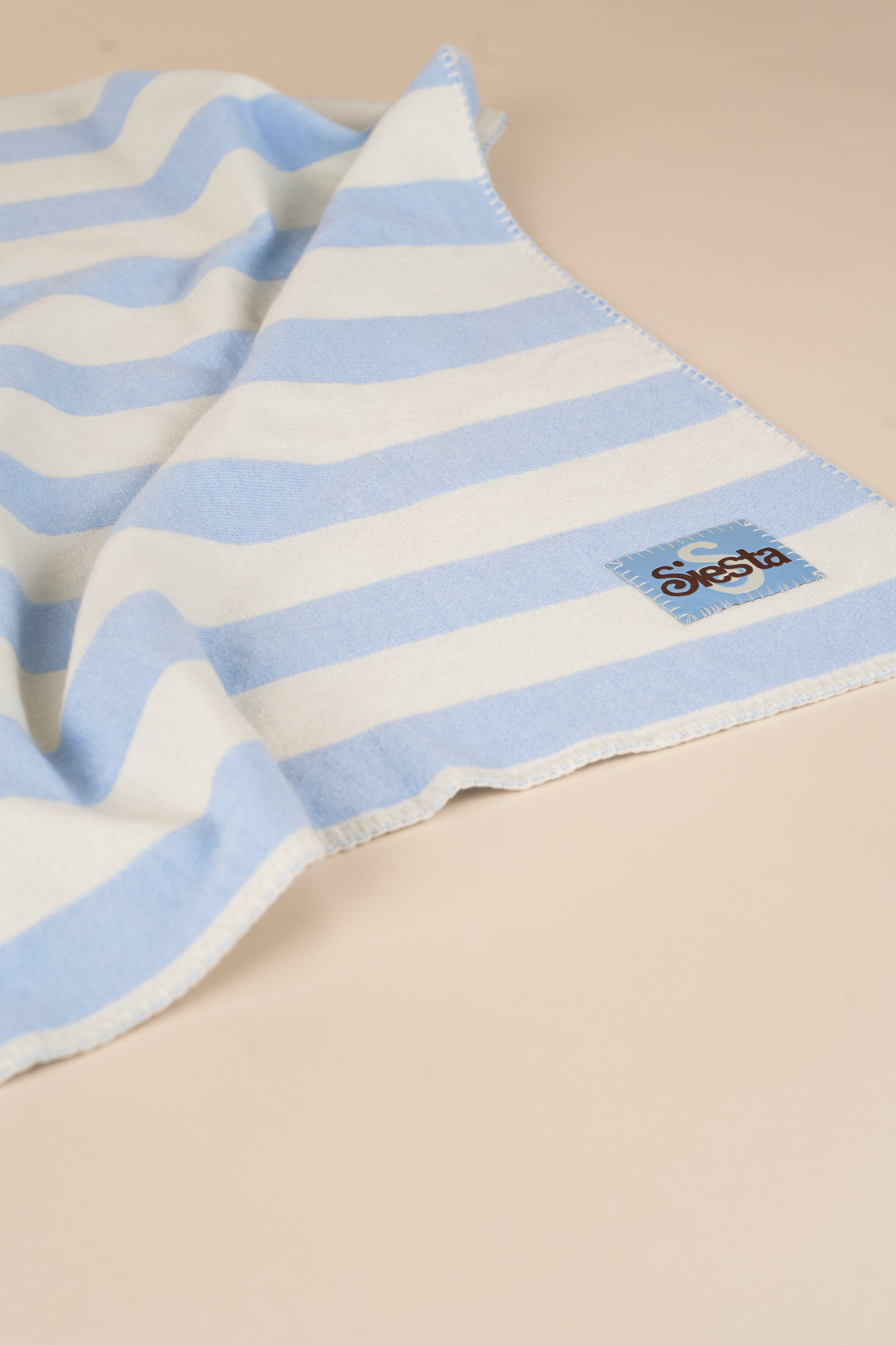 Striped blanket with a brand logo on a beige background