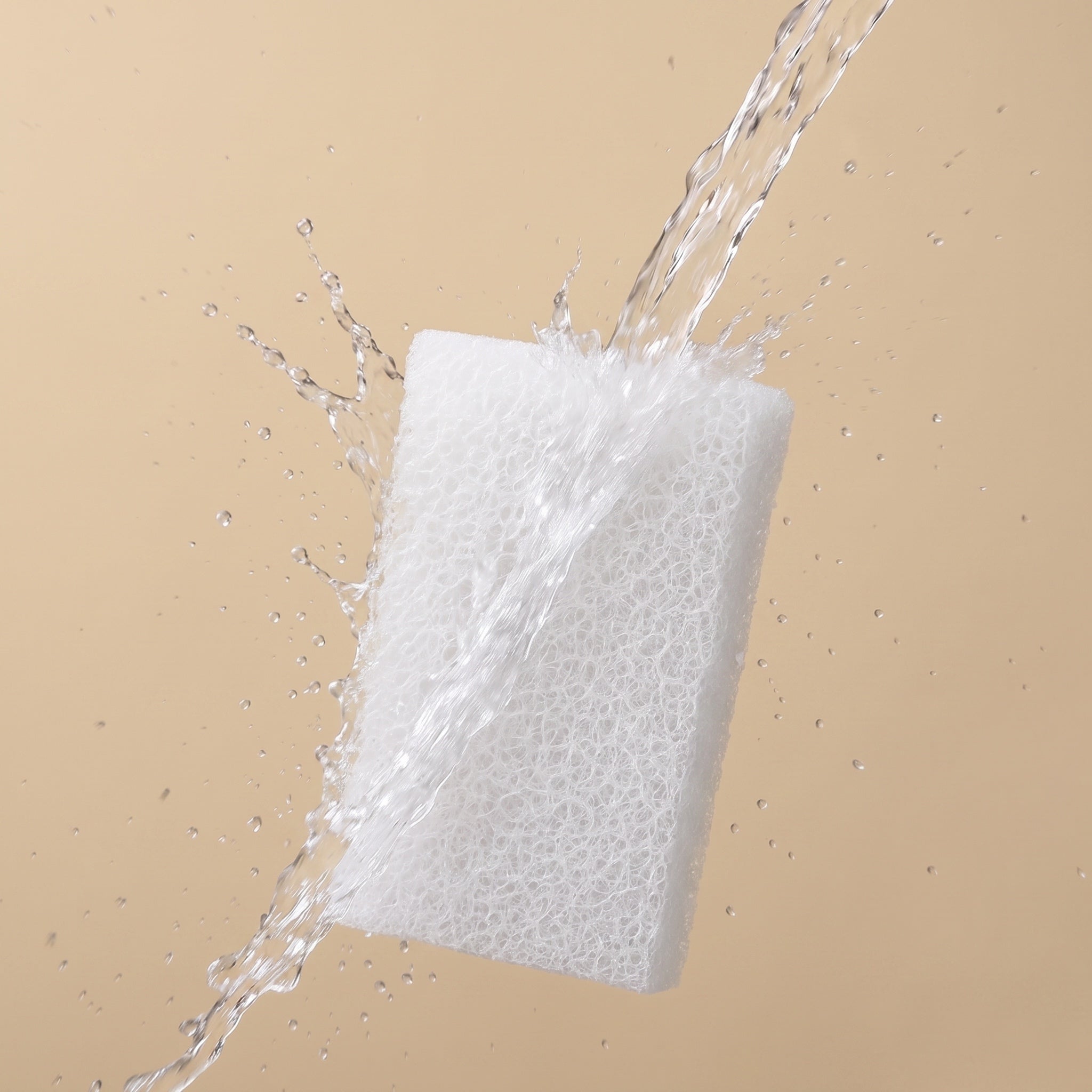 White sponge with water splashes on a beige background